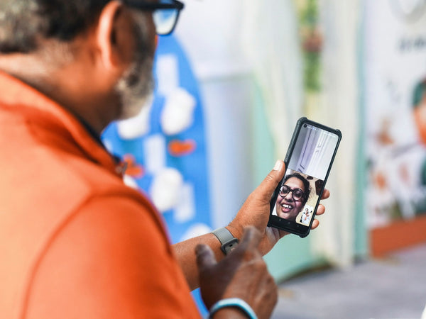 A man video calls a smiling woman on his phone