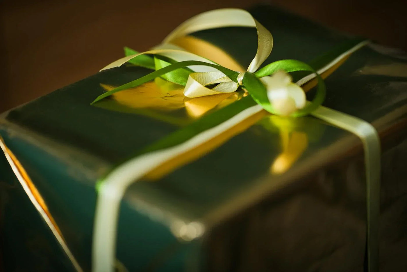 Elegantly wrapped gift box with gold ribbon in warm ambient lighting — romantic gift idea for couples