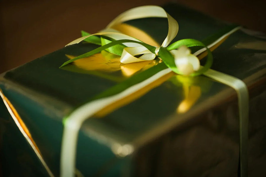 Elegantly wrapped gift box with gold ribbon in warm ambient lighting — romantic gift idea for couples