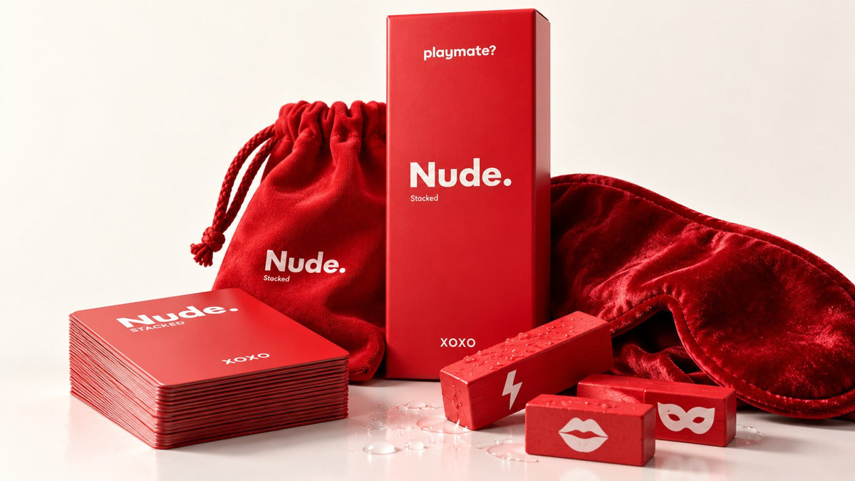 The Nude Stack'd couples game set: red box, prompt card deck, red symbol blocks, a velvet eye mask and drawstring bag