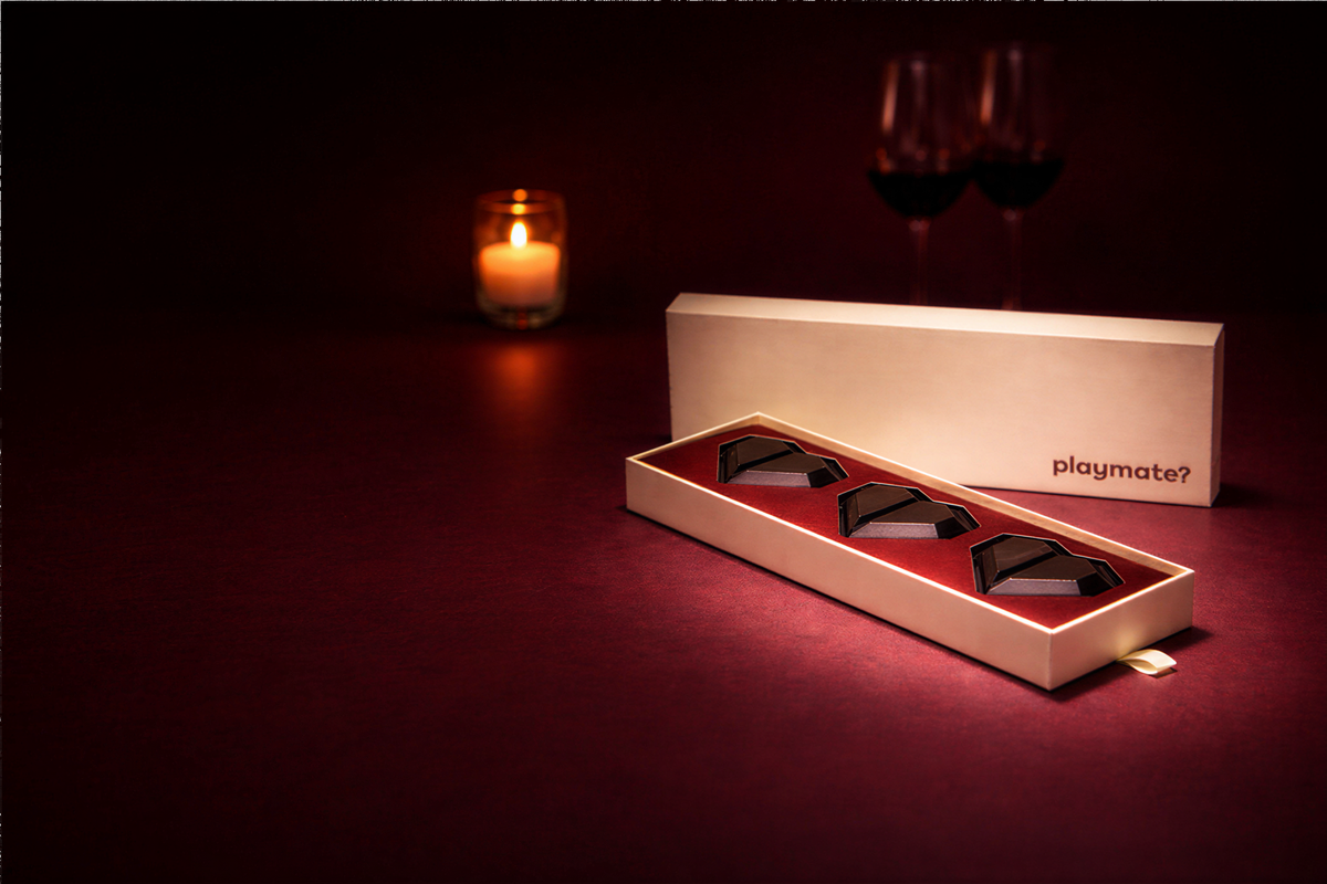 Box of Snap'd chocolate hearts by candlelight on a red table
